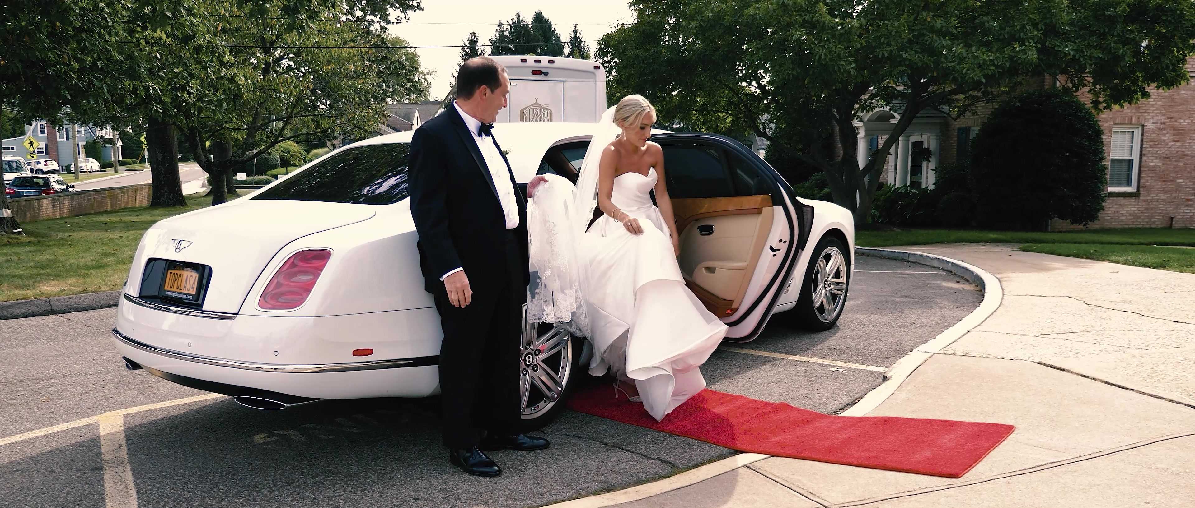 Couple stepping out of a vintage car onto a red carpet at the venue