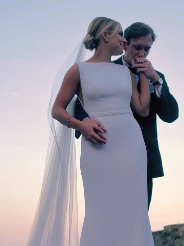 Bride and groom on a coastal cliff at sunset, her veil lifting in the wind, from a Main Street Drone wedding film